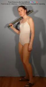 A white woman standing nonchalantly, a bat slung over her shoulder.