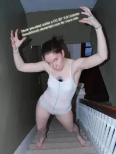 thine white female pose reference model standing on stairs from a high perspective with arms over her head fingers clawed