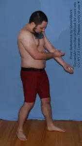A white man standing and simulating injecting himself in the arm