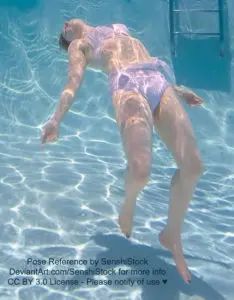A white woman wearing a light purple bikini floating upwards toward the surface of the water