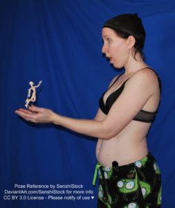 A white woman wearing a black bra and Gir pajama bottoms from the side, holding out her hands to the left, and cupping a small jumping figure in hand. She looks surprised.