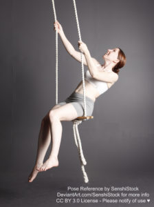 A white woman swinging on a suspended swing, holding onto both ropes with her hands.