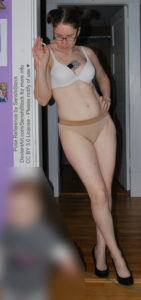 thin white female pose reference model standing in a doorway leaning against the doorframe with one hand on a hip the other by her face holding a cigarette