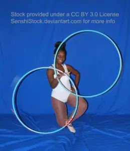 A Black woman, down on one knee, holding two blue hula hoops.