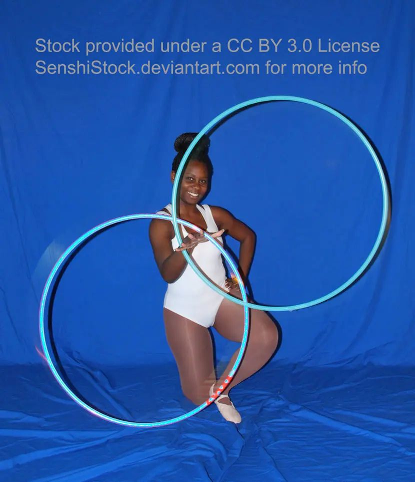 A Black woman, down on one knee, holding two blue hula hoops.