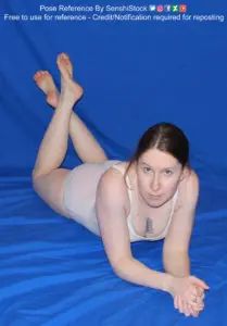 A white woman in foreshortening, lying on her stomach, hands clasped together, ankles crossed behind her.