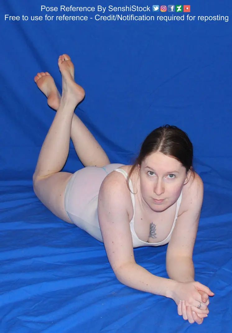 A white woman in foreshortening, lying on her stomach, hands clasped together, ankles crossed behind her.