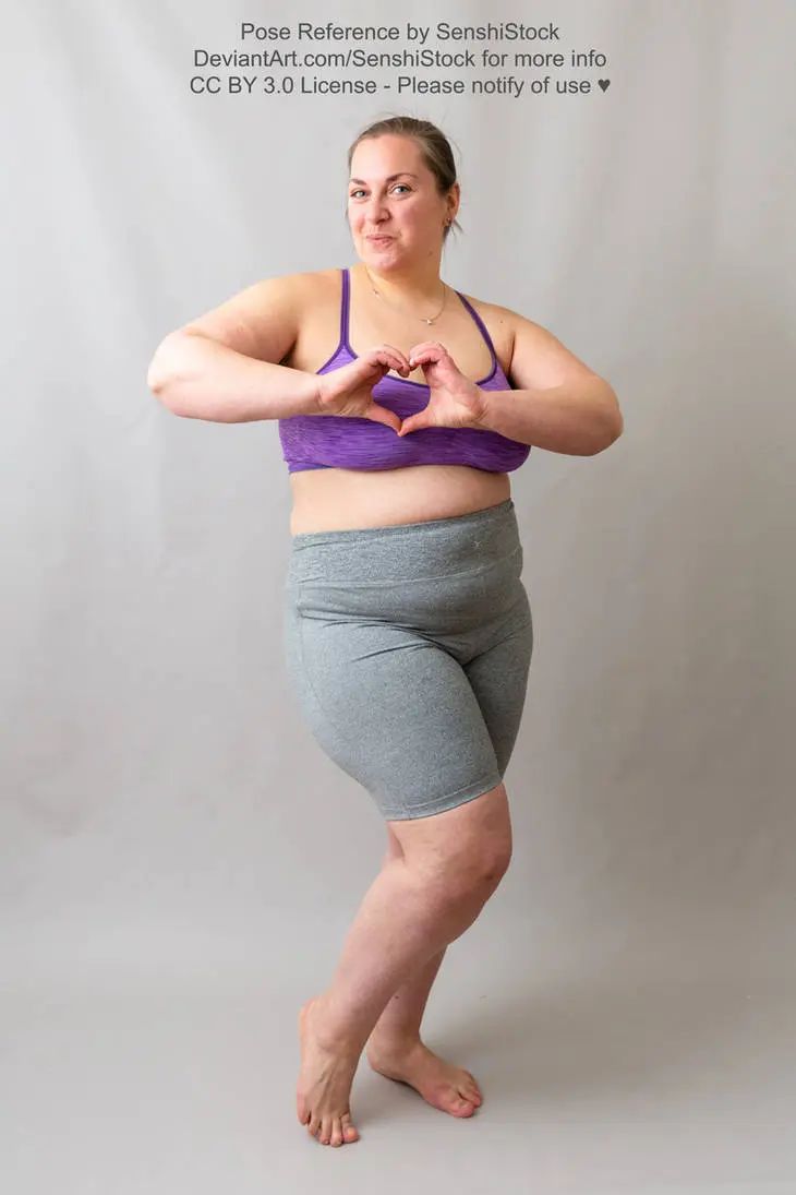 A fat white woman making a heart gesture in front of her chest and smiling