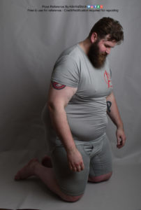A fat white model wearing skin tight clothing is on his knees, at a 3/4 angle, arms hanging limp at his sides, head down.