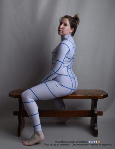 Thin white woman wearing a form-fitting zentai suit (full body outfit with lines to help with perspective), sitting in profile on a dark brown wooden bench. Her back is arched, emphasizing her curves, and her hands are resting between her thighs. She's looking slightly over her shoulder to the camera.
