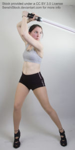 A thin, white, female model in high heels, shorts, and sports bra, standing with legs apart and arms raised overhead, holding a lightsaber. Her gaze is over her shoulder as if she's ready to fight.
