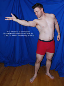 A muscular white man wearing a pair of red boxers is standing with his legs slightly apart. One arm is relaxed down, the other is out stretched, palm up, like he's reaching or casting a spell. The camera is at a slight downward angle.