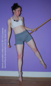 White woman holding a staff in her right hand, floating, her legs outstretched.