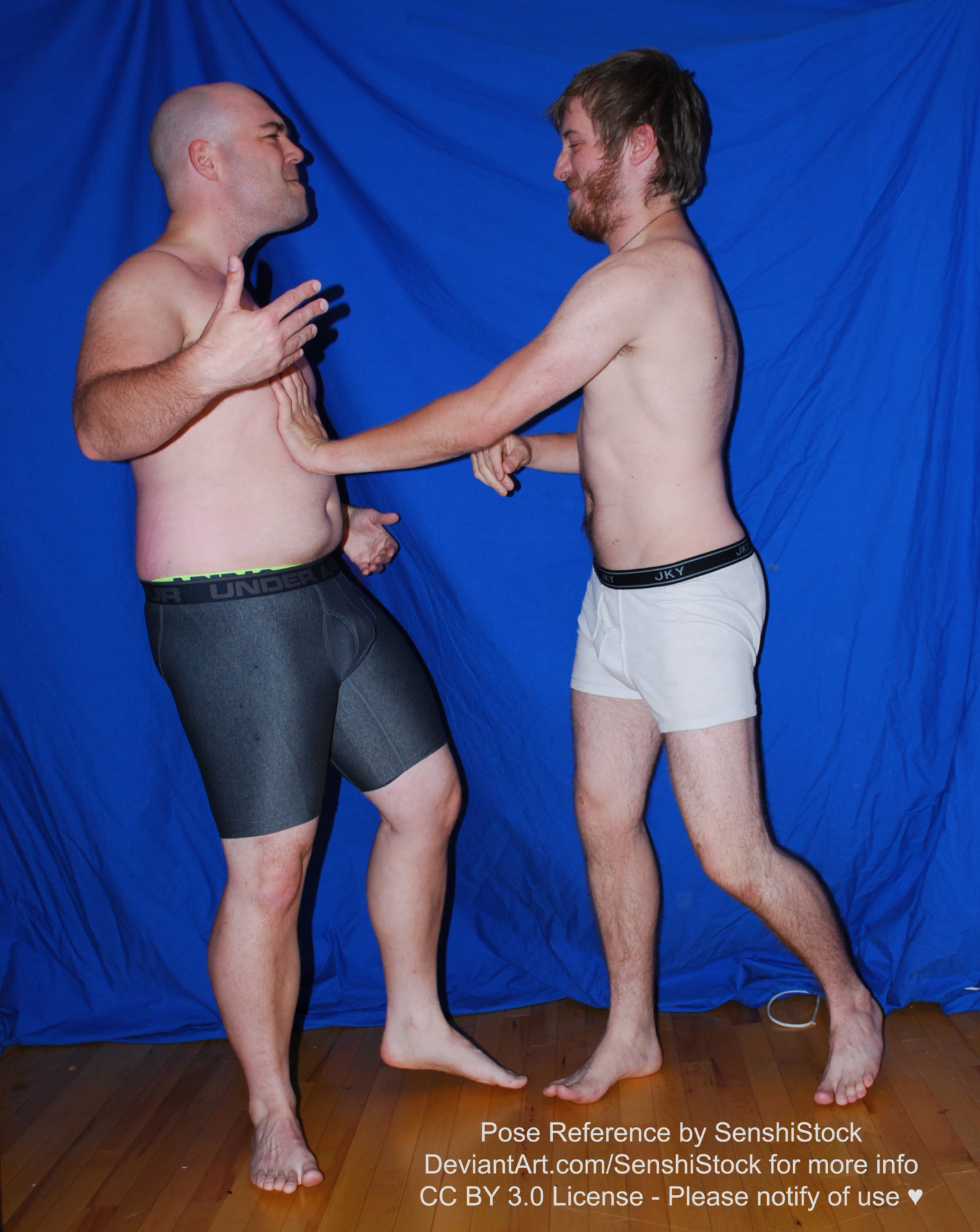 Two white men with boxers who are fighting with each other. One has his arms raised as the other presses a hand against the other's chest.