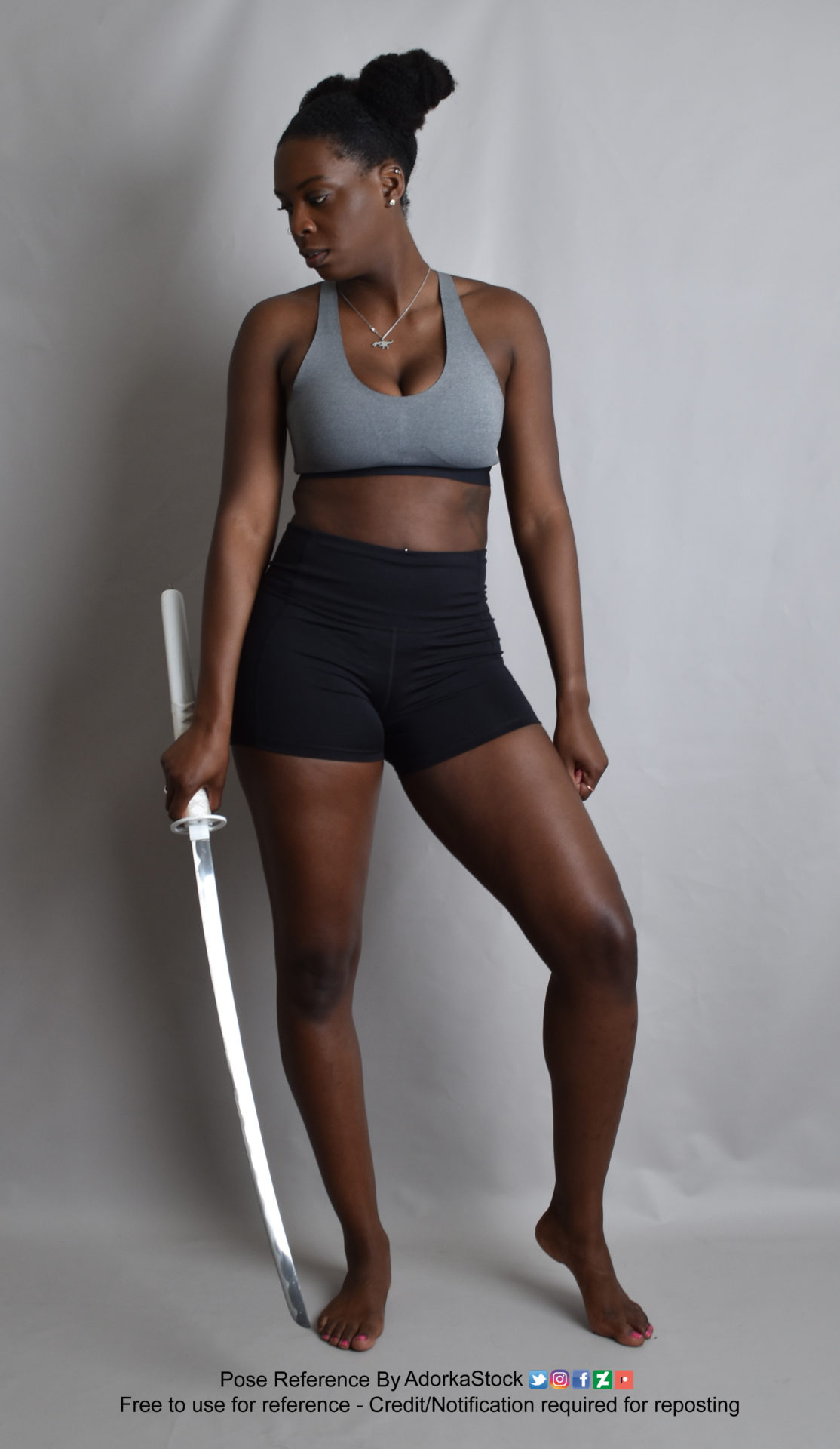 Thin, Black, female model standing with weight shifted to one foot, holding a katana in her right hand, looking down and off to the right.