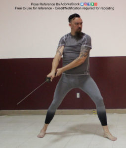 Tall, fit, white, male model holding a katana back behind him to the side