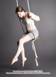 Thin, white, female pose reference model sitting on a swing with legs hanging