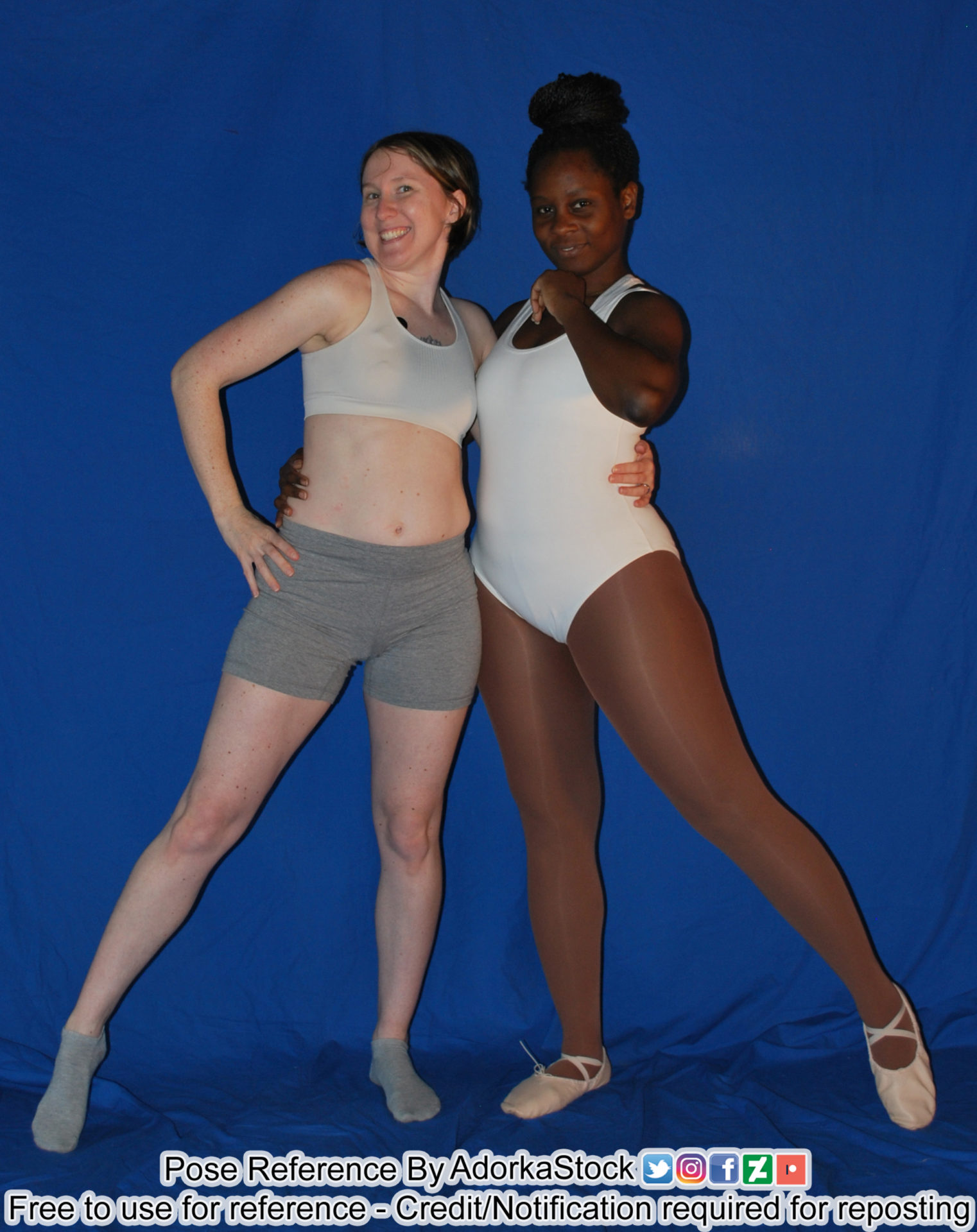 Two fit pose reference models, one white one black, standing together with arms around each other looking cute together
