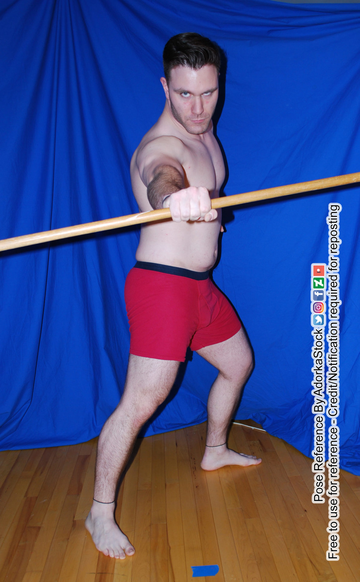 Fit, male pose reference model with one hands towards the camera holding a staff