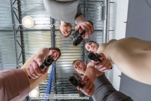 a group of four pose reference models from the waist up pointing firearms at the camera, the figures are towering over the camera's point of view