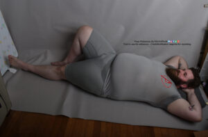 Male model Klaus lying on his back with his arms under his head, left leg stretched out and the right bent