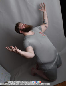 Model Klaus kneeling with his arms raised in the air like he is yelling, mourning or has been defeated. Taken from a high angle