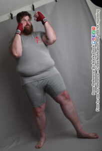 Model Klaus with hands wrapped in red tape, hands up in a defensive position like he's about to box or fight MMA