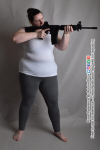 Model Shae aiming rifle to the right with one eye closed