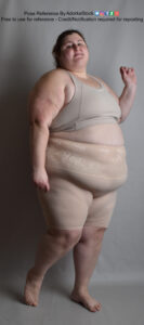 Fat, white, female pose reference model in standing pose with one arm raised.