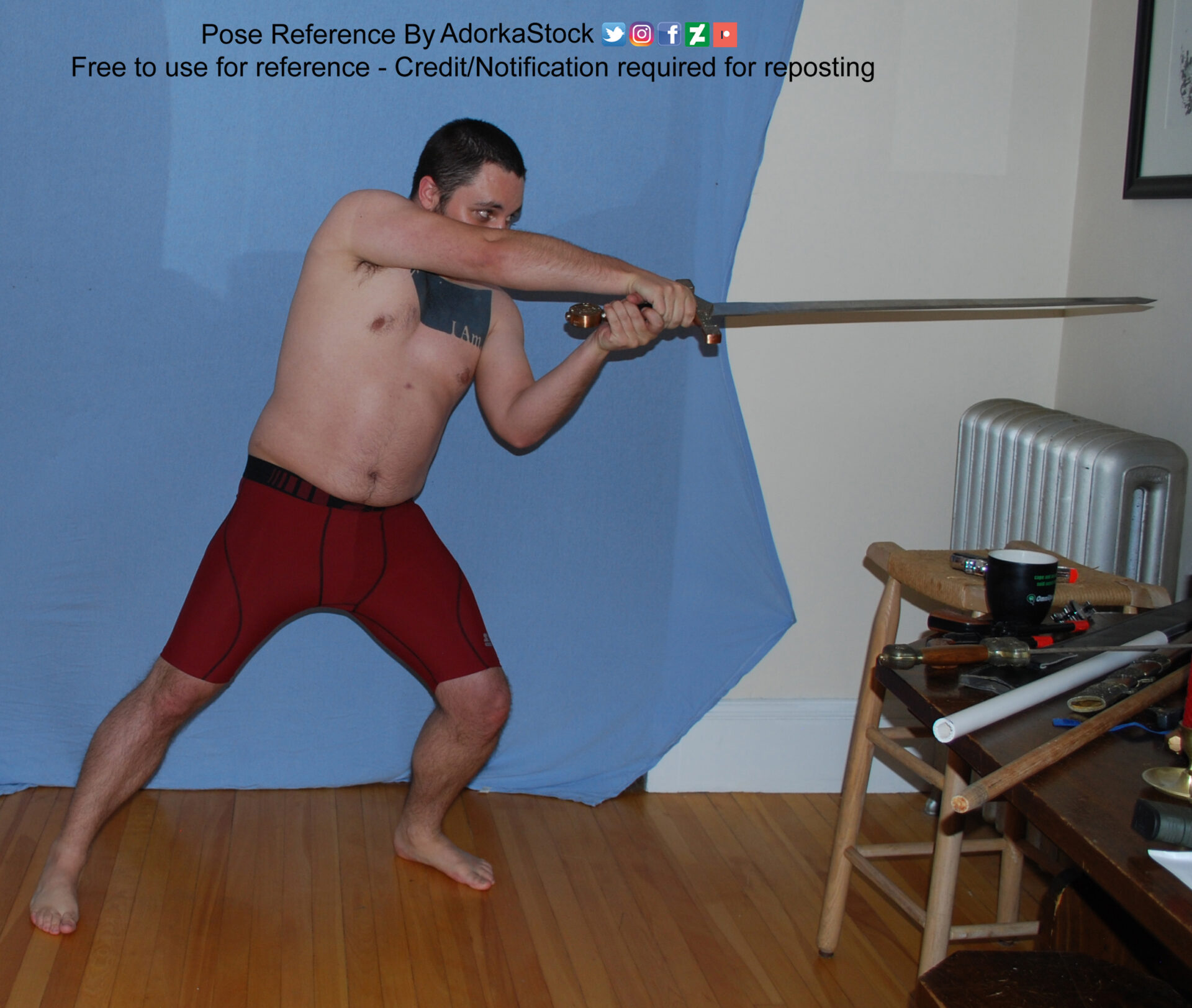 Stocky, tan, male pose reference model in standing lunge pose with a sword.