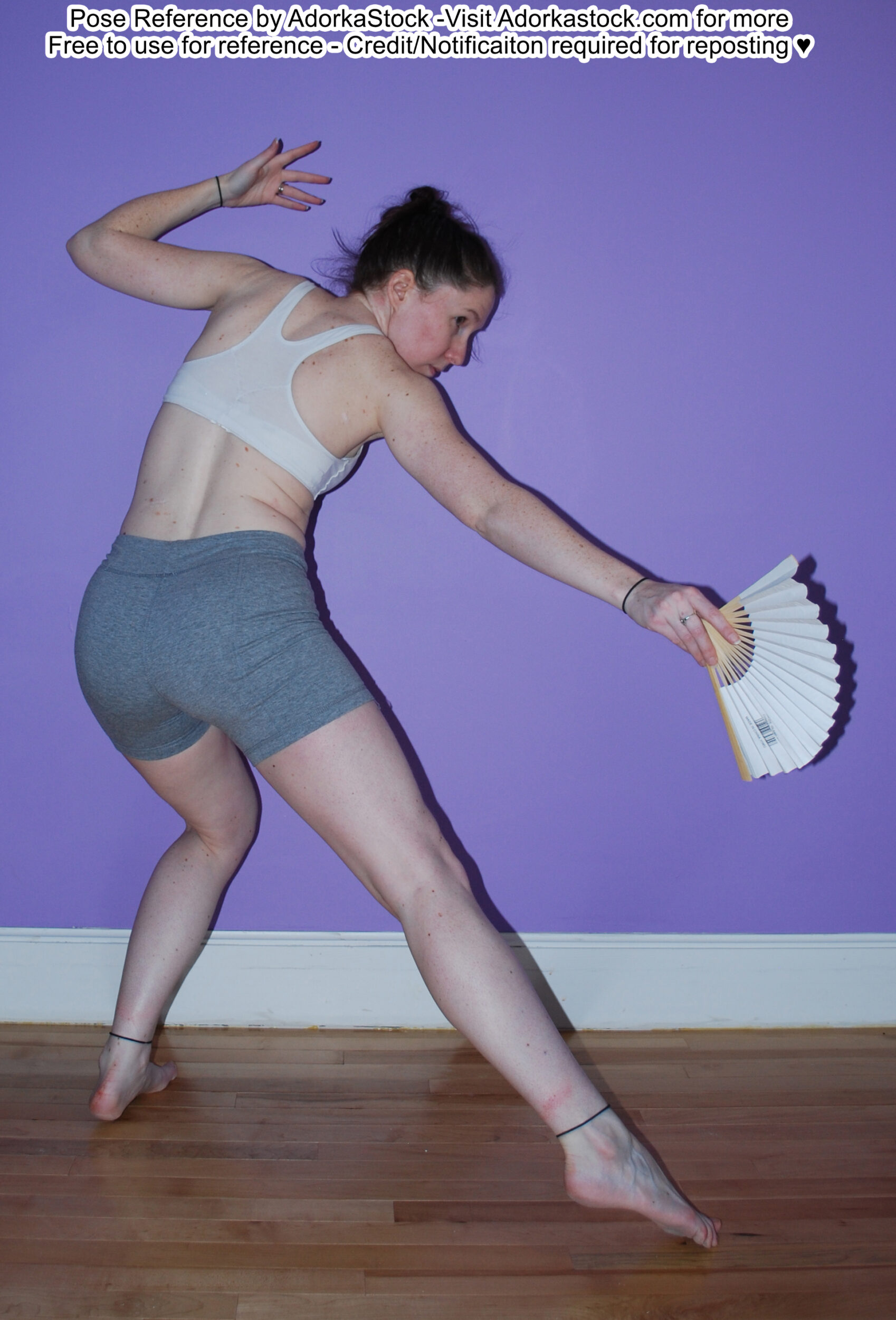 Thin, white, female pose reference model in ack facing dynamic lunge pose with a fan held out to the side, the other arm raised.