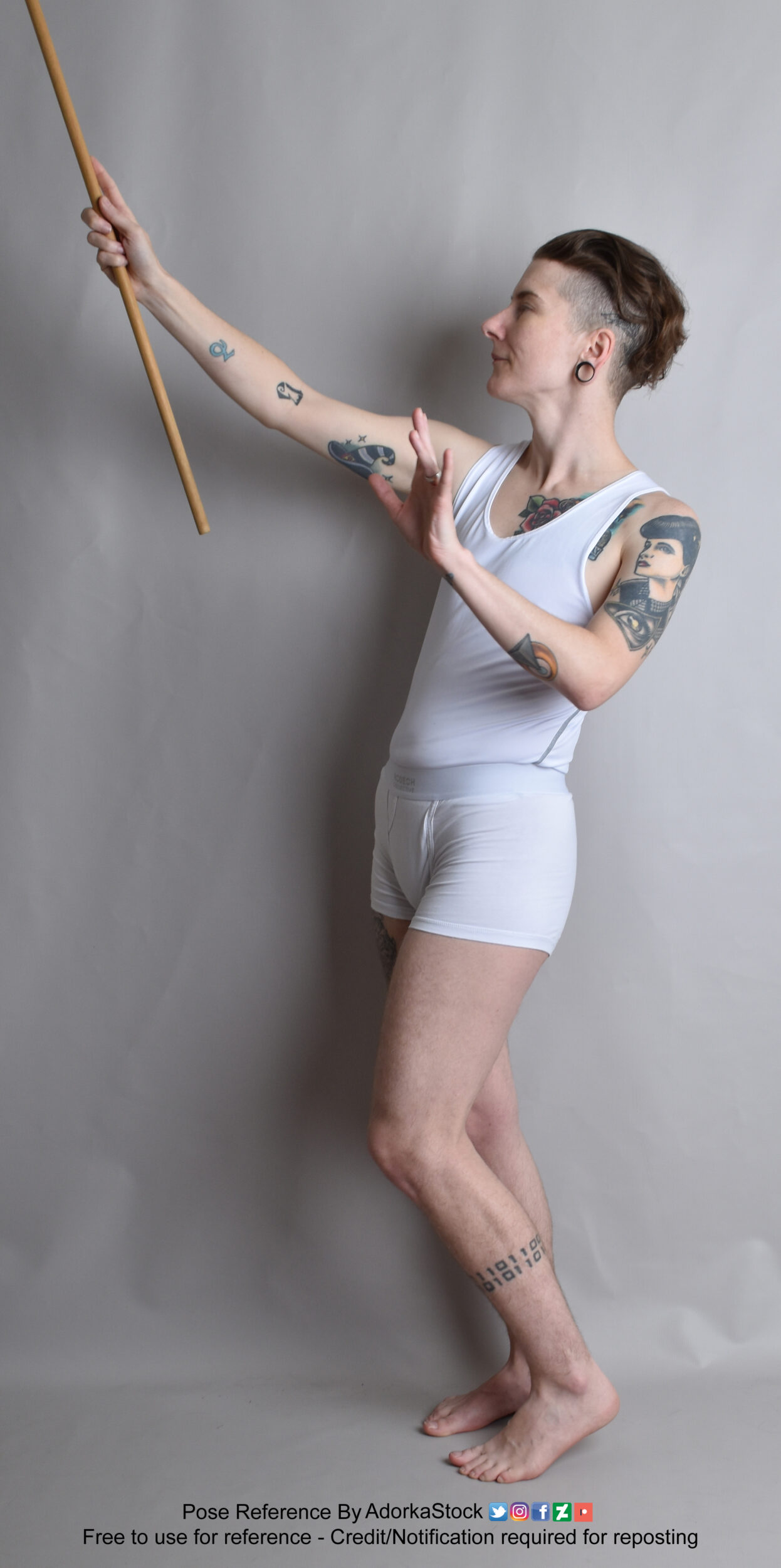 Thin, white, nonbinary pose reference model in standing profile pose with stick raised as if casting a spell, the other hand open.