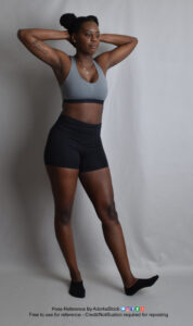 Thin, Black, female pose reference model in casual standing pose with hands behind her head.