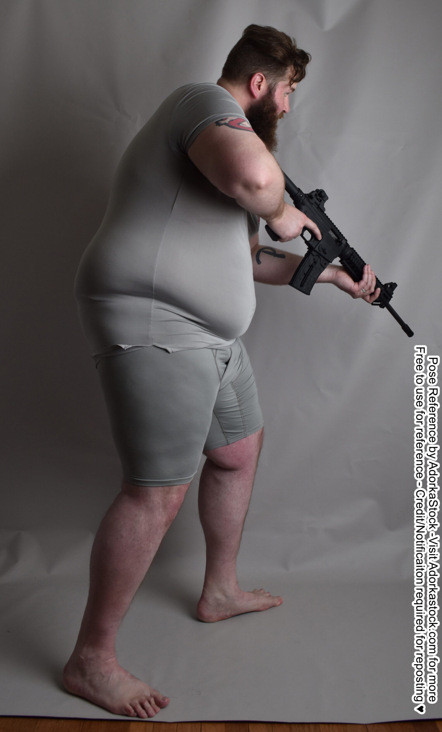Fat, white, male pose reference model in back facing pose with a long gun.
