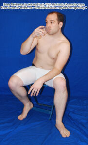 fit, white, male pose reference model in sitting chair pose with a glass of water to his lips