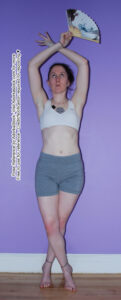 thin, white, female pose reference model in standing pose with legs and arms crossed, holding a fan