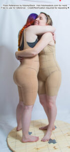 Two white, female pose reference models in a hugging pose