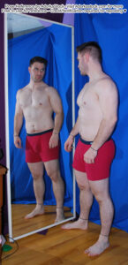 fit, white, male pose reference model in standing pose looking at his refection in a mirror