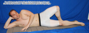 Fit, white, male pose reference model in reclined pose with head propped up on one hand.