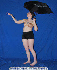 thin, white, female pose reference model in standing pose with an umbrella, one hand out as if to feel rain