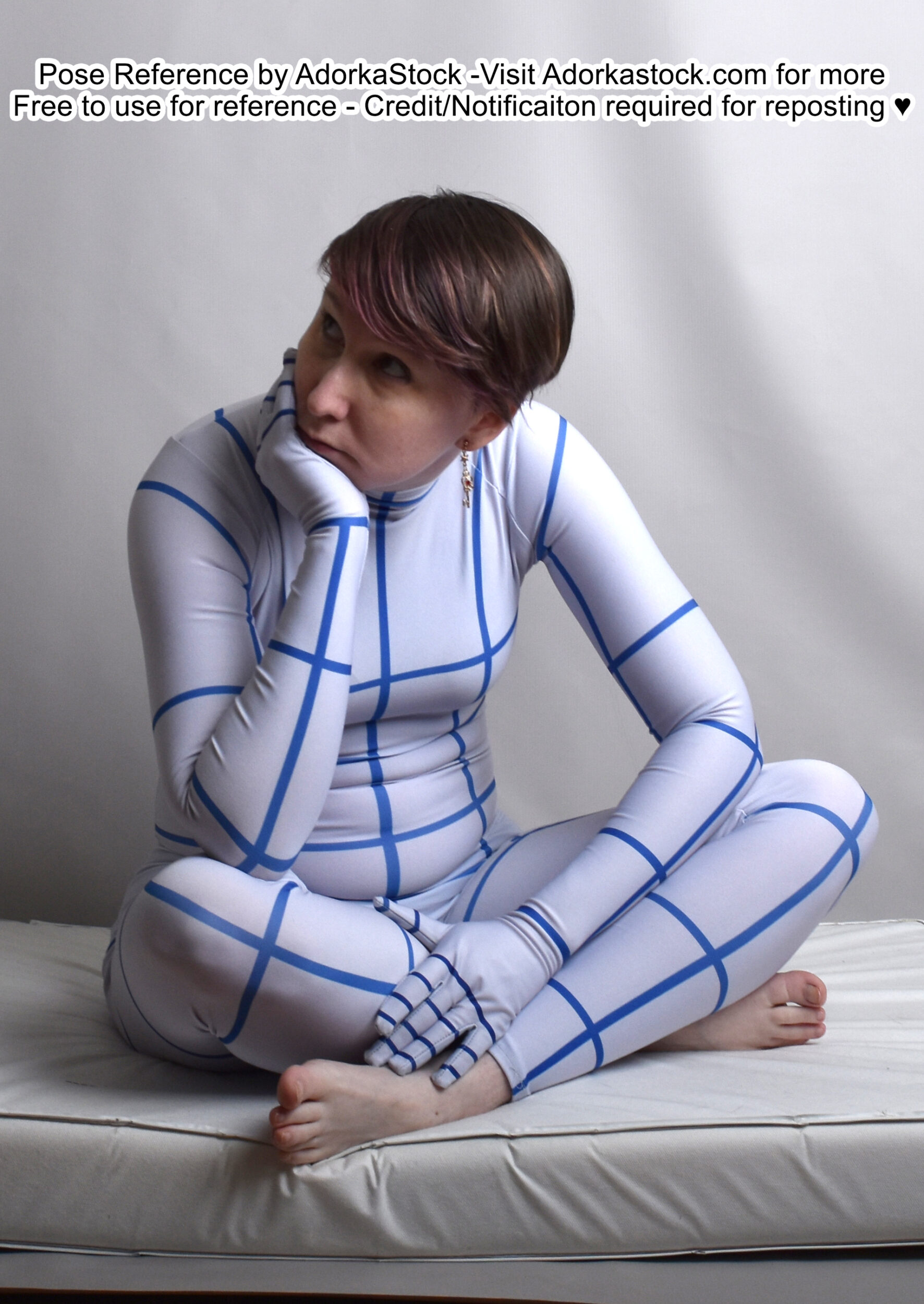 thin, white, female pose reference model in grid suit in a sitting pose with legs crossed and one hand under her chin