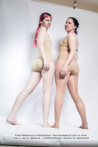 Two thin, white, female pose reference models in low perspective, standing, back facing pose with sneers