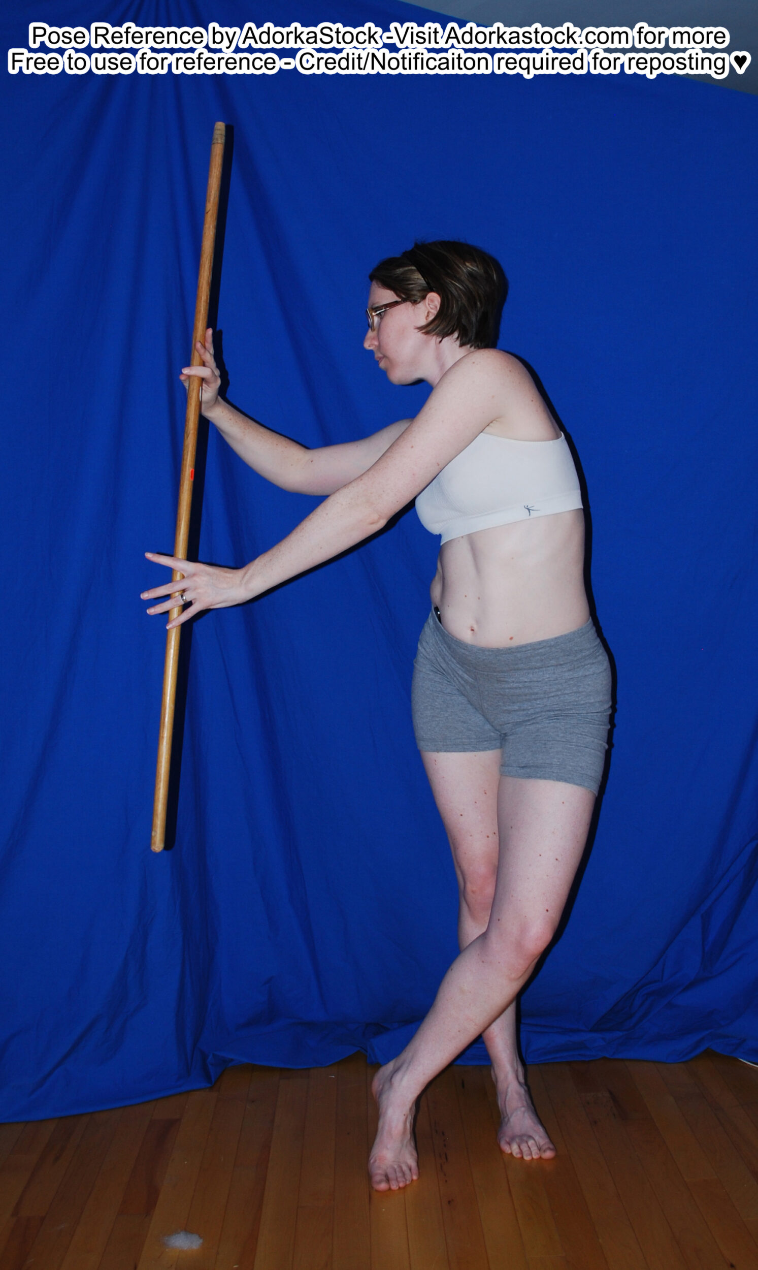 thin, white, female pose reference model in standing, twisting pose with staff prop