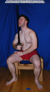 fit, white, male pose reference model in sitting pose, licking his sword (an actual sword, like a blade weapon)
