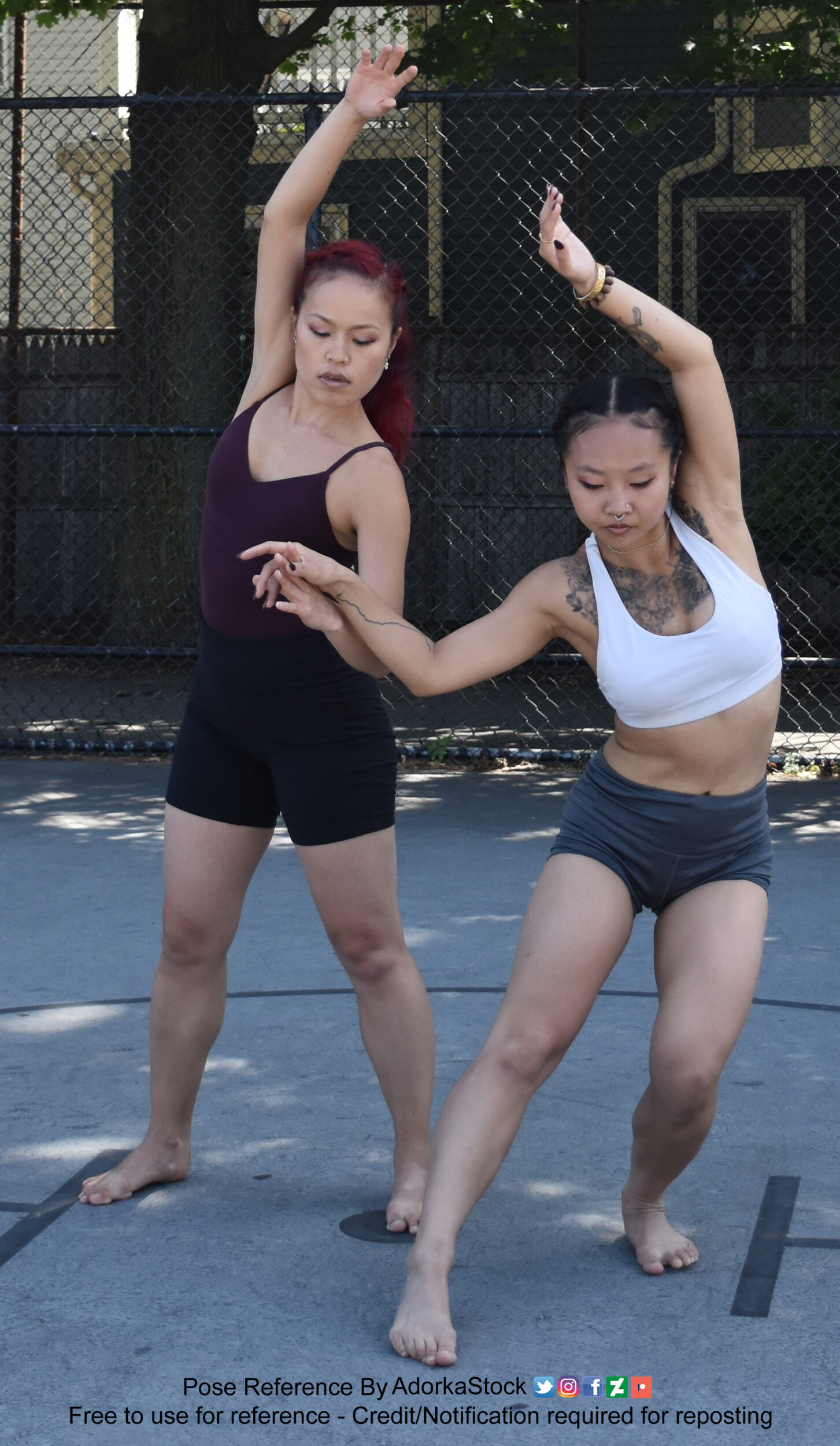 Two thin, Asian, female pose reference models in dancers poses with hands linked.