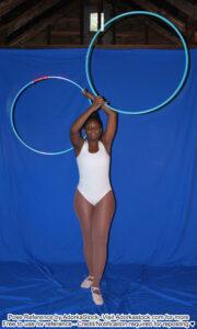thin, Black, female pose reference model in standing pose holding two large hoops above her head