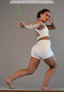 fit Latina pose reference model in standing back facing pose with upper body twisted back, holding a wand in one hand, the other by her face
