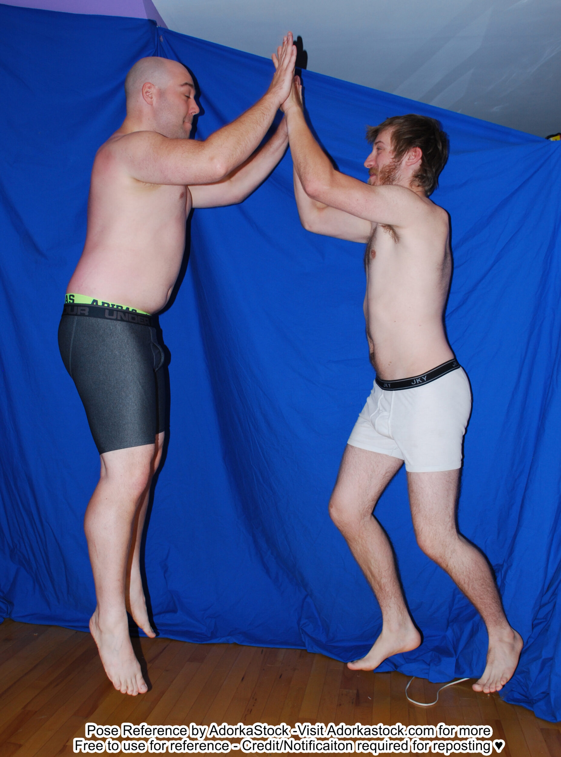 two, white, male pose reference models in a jumping double high five