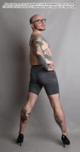 Thin, white, male pose reference model standing facing away in high heels, hand on hip, head turned back over the shoulder