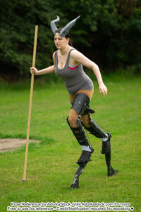 Pose reference model wearing Digitigrade leg extensions and horns, walking with a long staff